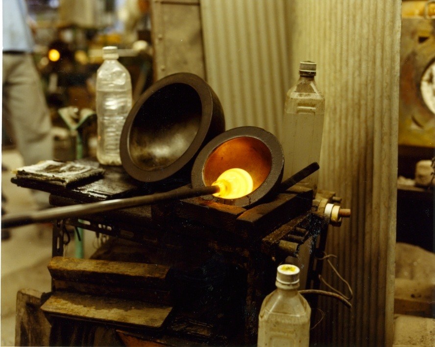 Molten glass glowing yellow-orange inside wooden moulds at Shotoku's glass-blowing factory.