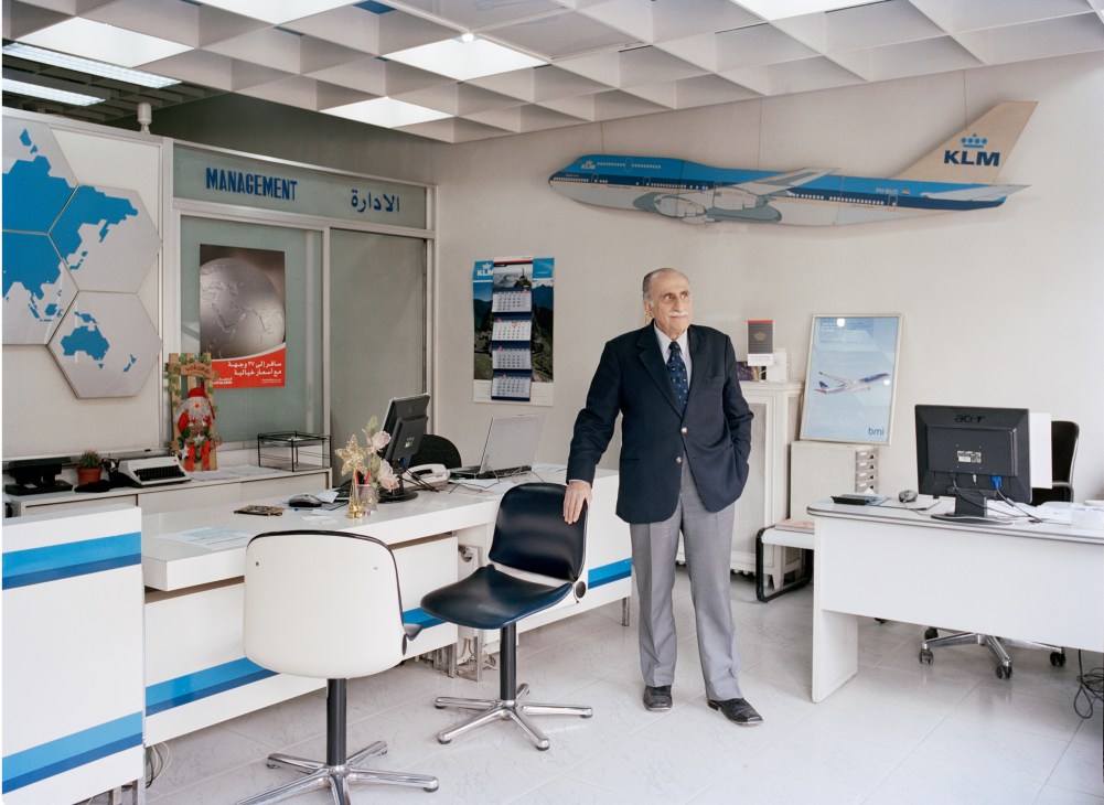 KLM agent Fuad Hilal stands in a modern office with KLM branding and aircraft model displays.