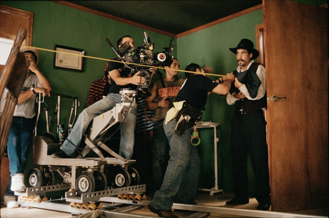 Film crew setting up camera equipment on a dolly in a green-walled interior for the movie Tequila.