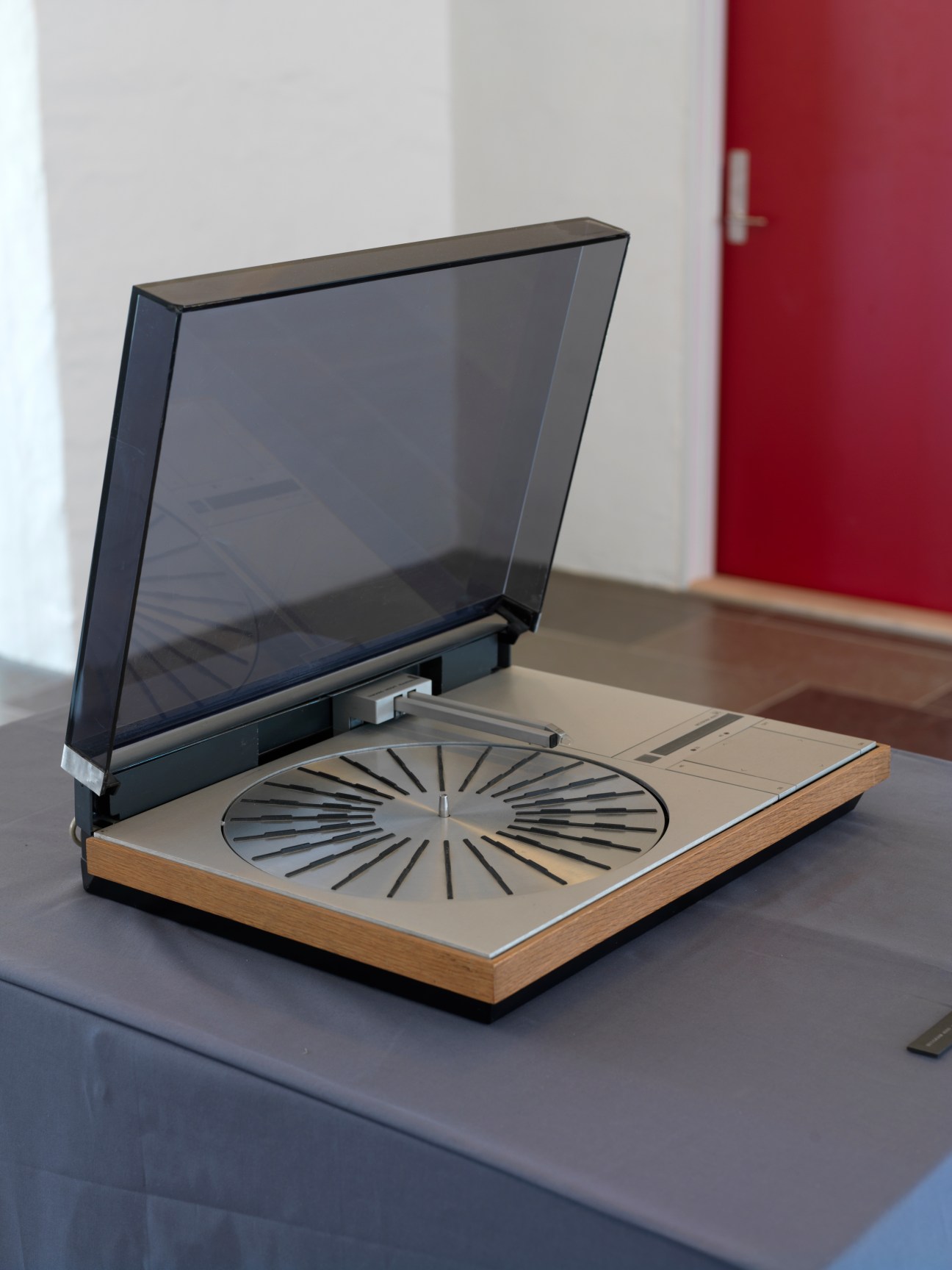 Bang & Olufsen BeoGram 4000 record player with teak base, cream platform, and dark hinged lid displayed in a modern showroom.