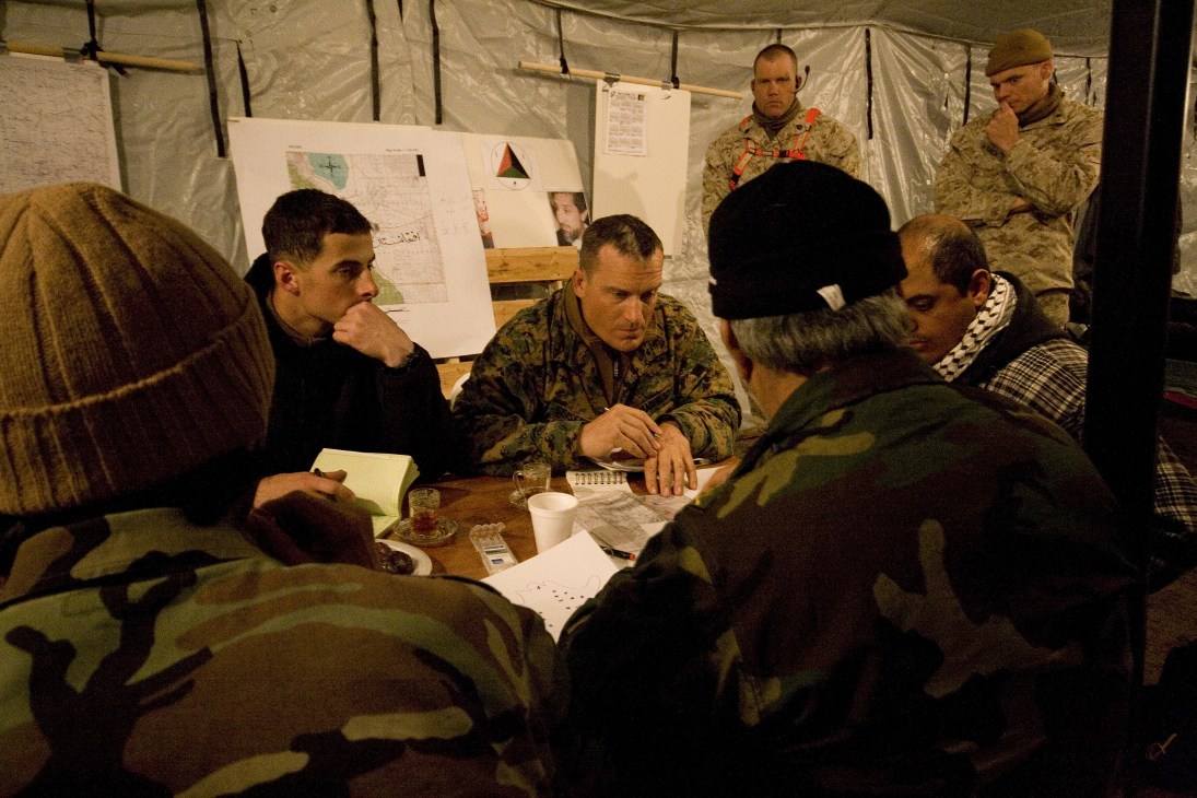 Marines and Afghan role players discuss raid plans over tea inside a tent during Mountain Viper training exercise in Nevada.