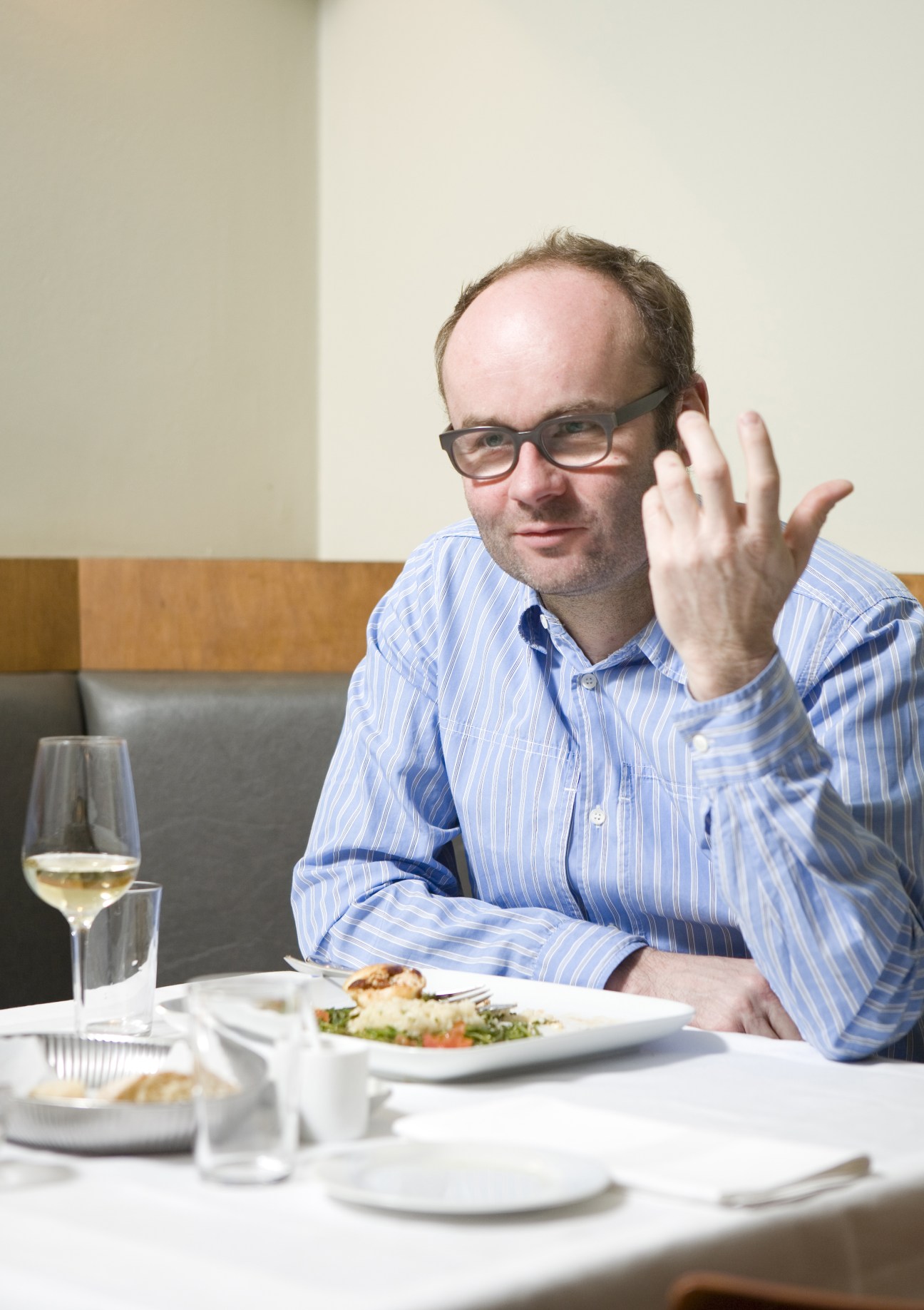 Thomas Demand dining at Cantamaggio restaurant, gesturing while seated at a table with wine and food.