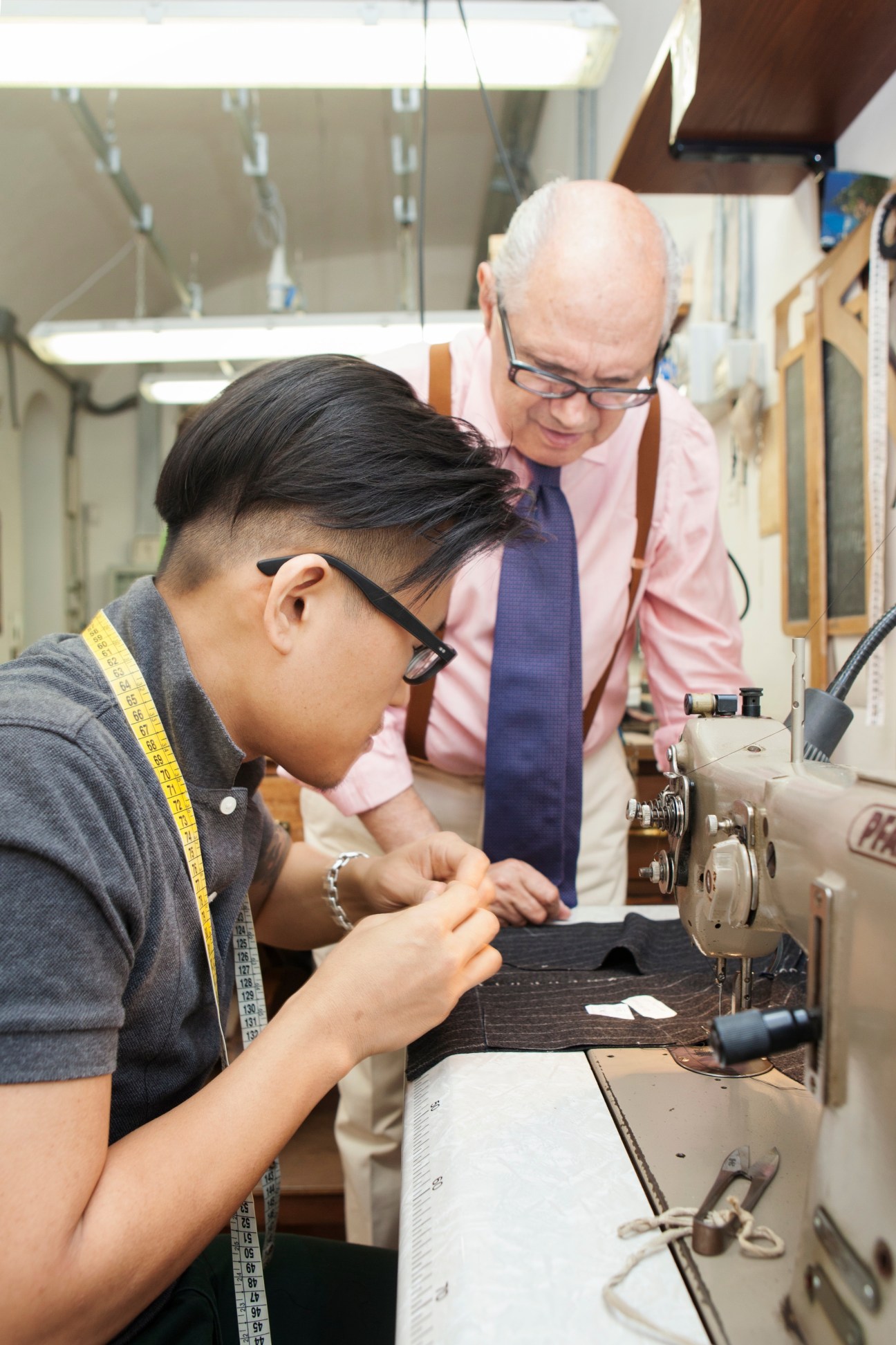 Senior apprentice Hojun Choi operates a sewing machine under the guidance of master tailor Antonio Liverano at Liverano & Liverano in Florence.