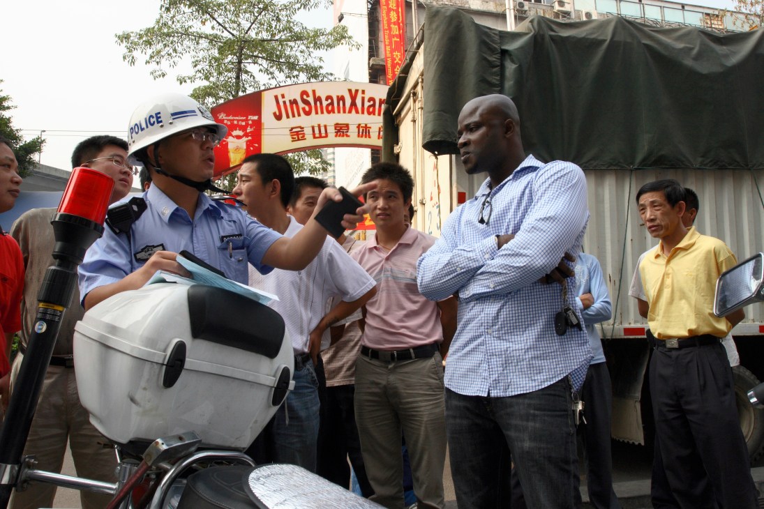 An African man in a blue shirt speaks with a Chinese police officer during a traffic stop in Guangzhou.