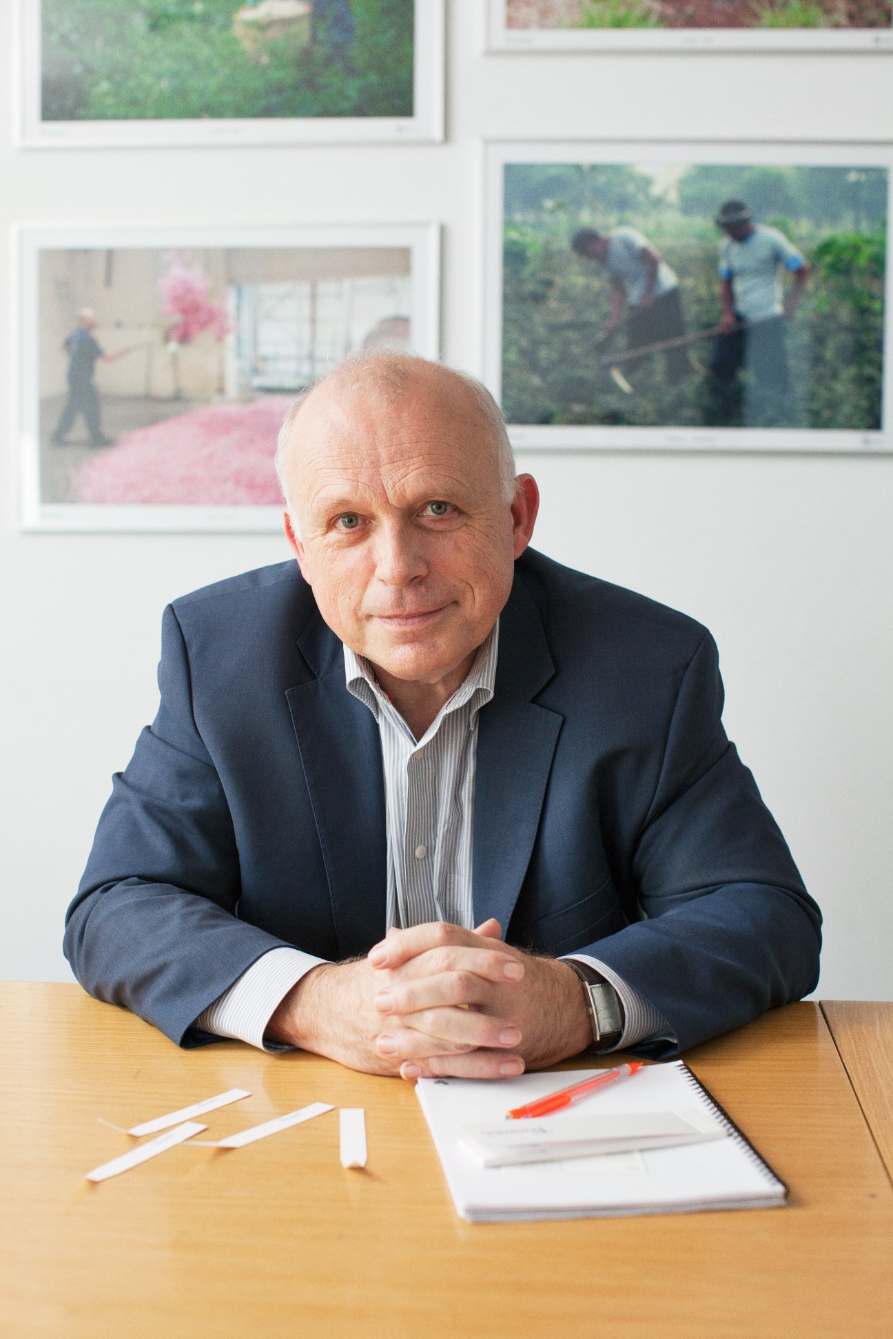 Dominique Roques, president of Firmenich Grasse, sits at a wooden desk with papers and a red pen.