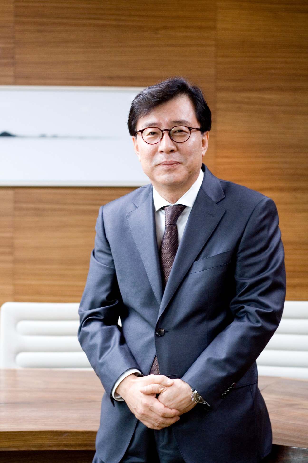 Kun Hee Ahn, president of Innocean, stands in the office wearing a dark suit and glasses.