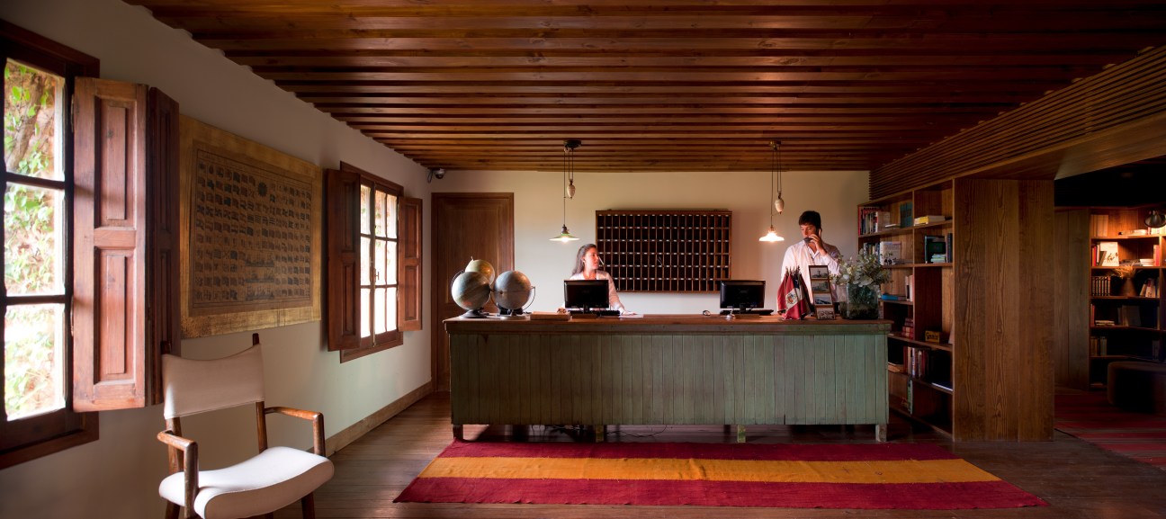 Las Piedras Fasano hotel lobby with wood-panelled walls, reception desk, and staff in rustic-chic interior.