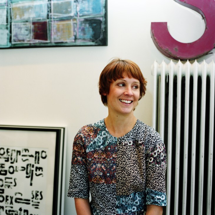 Anna Lena Mayor Ekeblad smiling in her Gothenburg studio-shop surrounded by artwork and a decorative pink element.