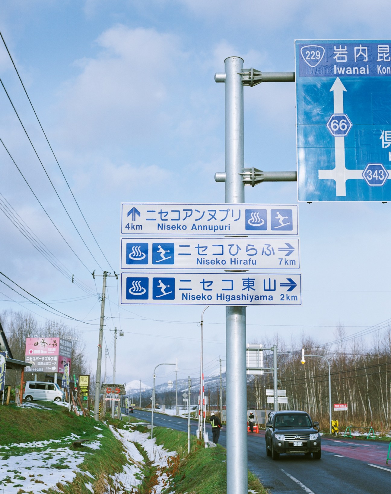 Bilingual road signs with Japanese and English text directing drivers to Niseko ski areas.