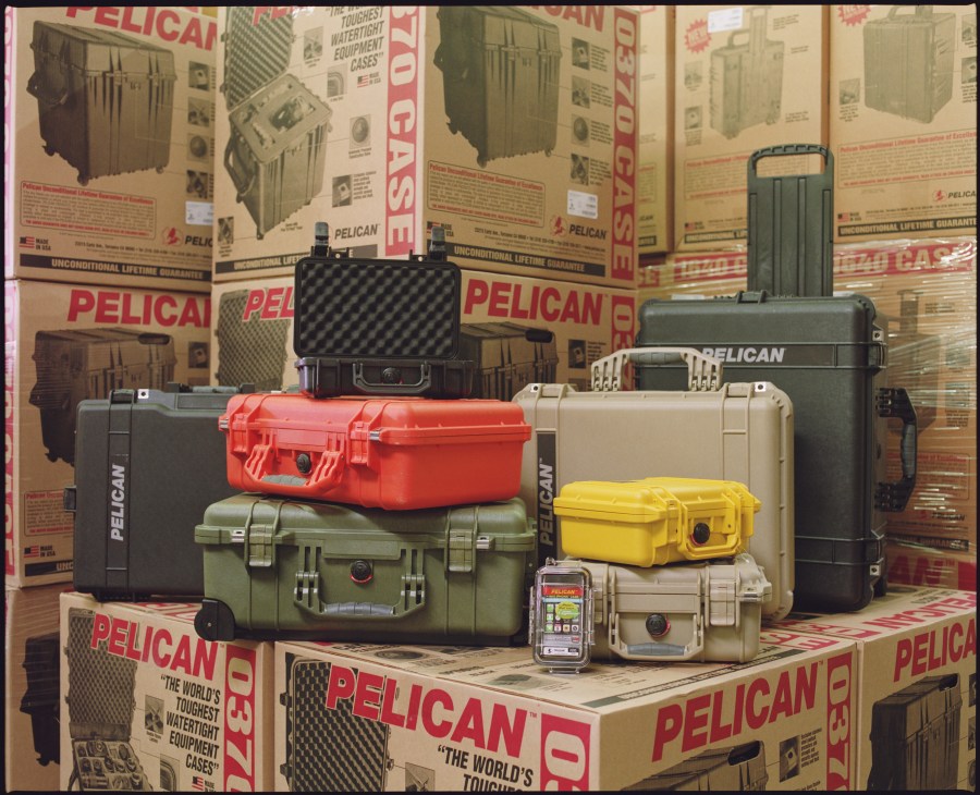 A selection of colorful Pelican protective cases in various sizes displayed in a warehouse.