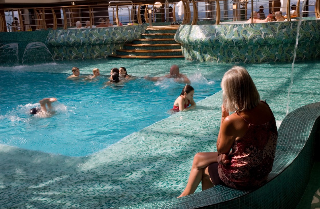 Passengers swimming and relaxing in the covered pool aboard the MSC Fantasia cruise ship.