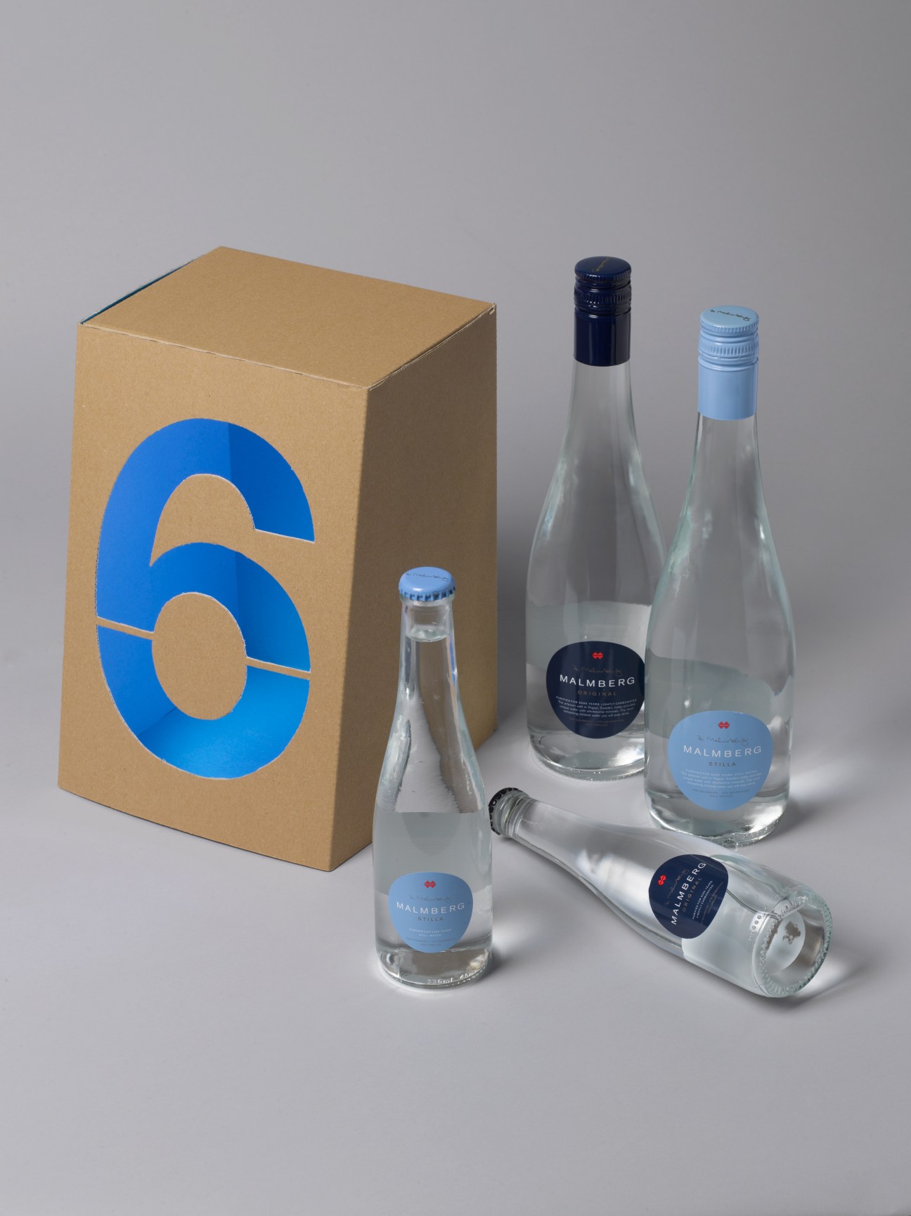 Malmberg lightly carbonated mineral water bottles with branded labels displayed with kraft packaging box.