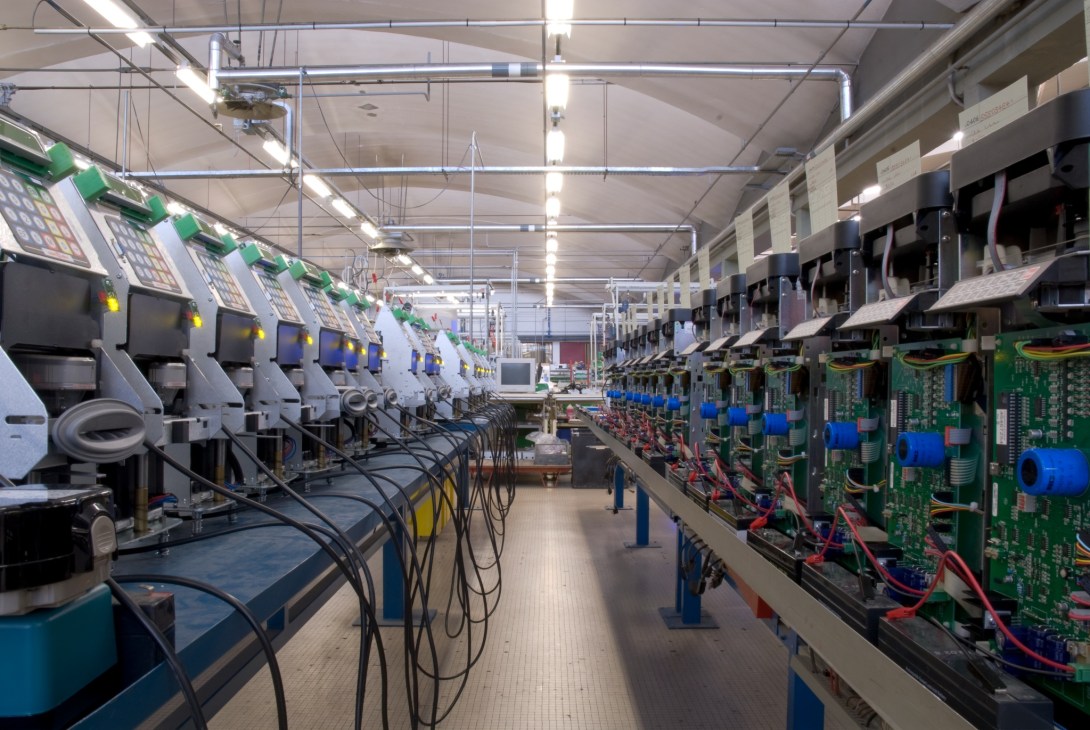 Factory floor showing rows of Solari ticket machines for SNCF with electronic components and wiring.