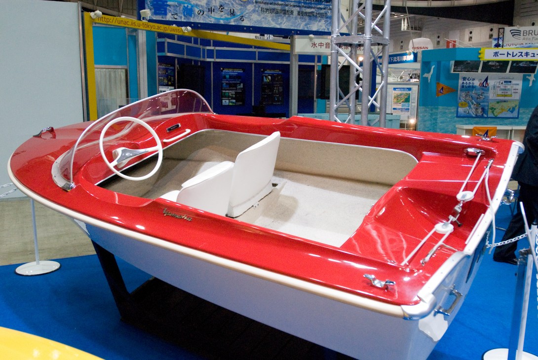 Red and white personal watercraft with steering wheel displayed at boat show