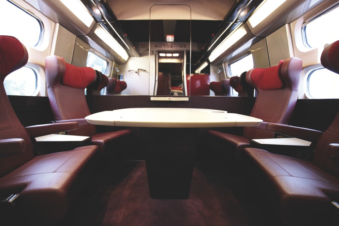 Interior of Thalys high-speed train meeting room with red seats and white table.