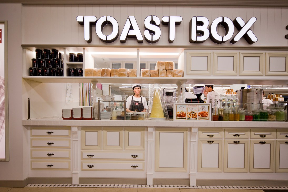 Toast Box storefront in Singapore with staff visible behind counter and packaged products on display shelves.