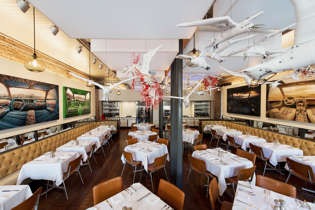 21c Museum Hotels restaurant interior with contemporary art installations and white tablecloths.