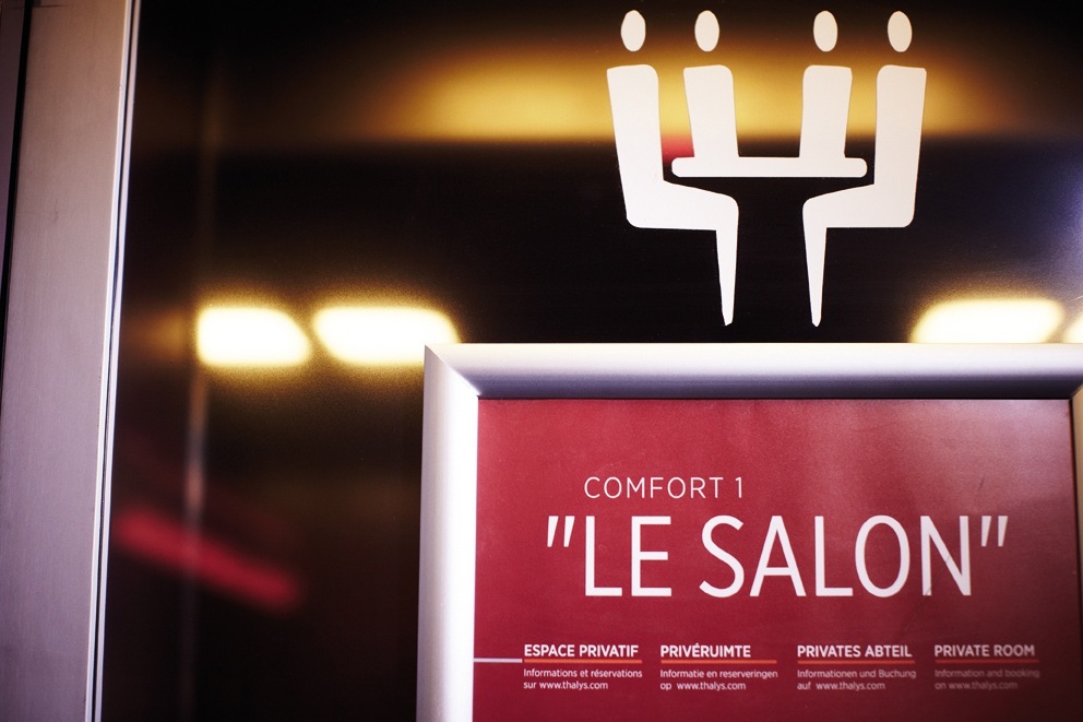Illuminated sign for Thalys train's 'Le Salon' private meeting room with four white chair silhouettes.