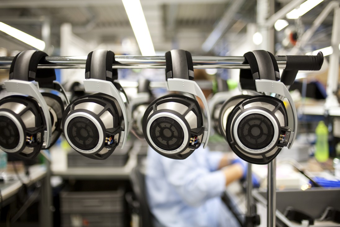 Sennheiser HD 800 headphones suspended on a manufacturing line in a factory setting.
