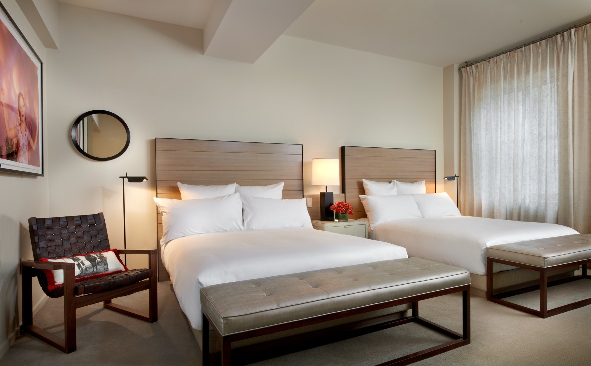 Modern hotel room with two queen beds, wooden headboards, contemporary furniture and neutral decor at 21c Museum Hotels Louisville.