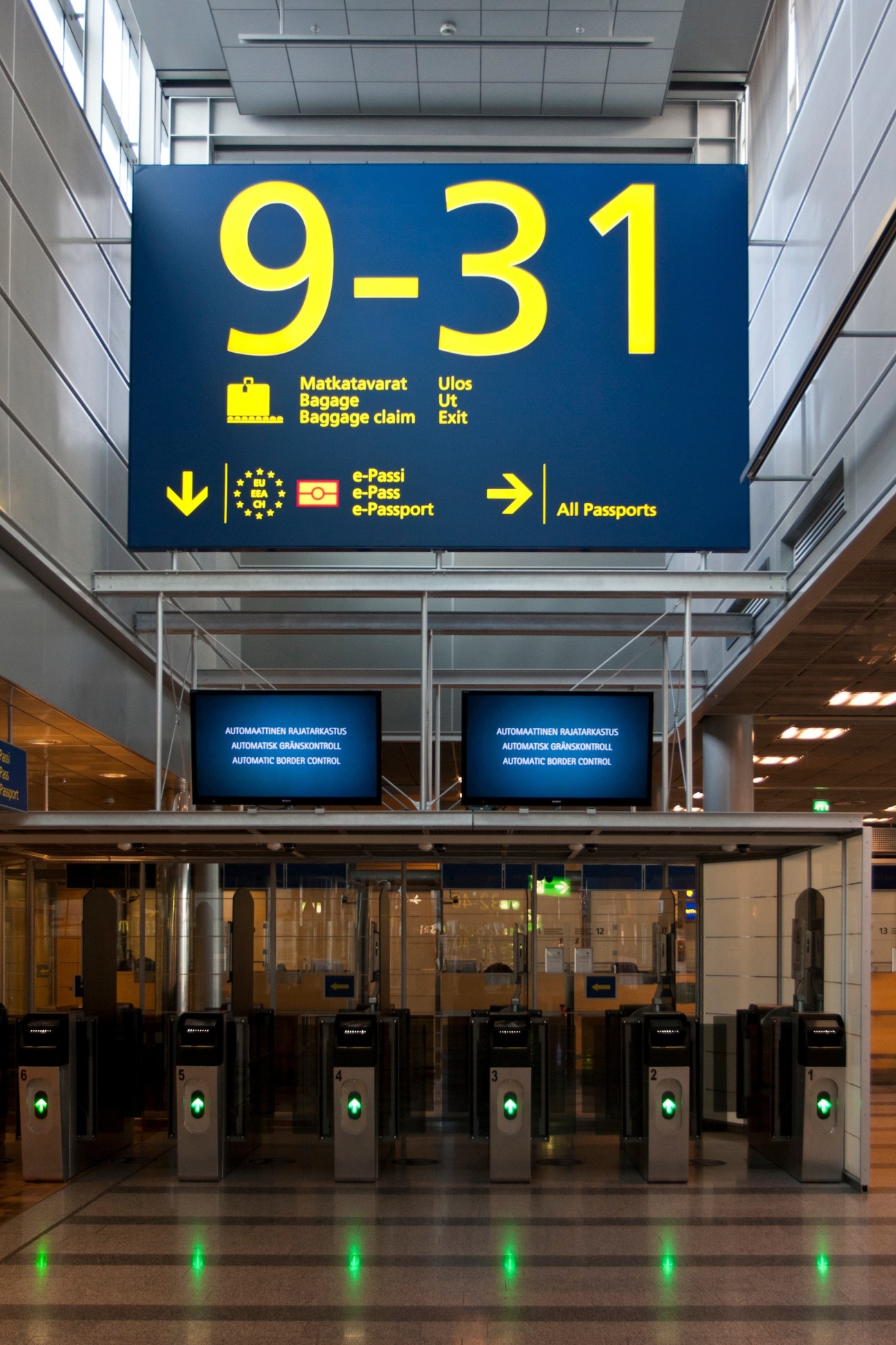 Airport wayfinding sign displaying gate numbers 9-31 with directional icons for baggage claim and passport control.