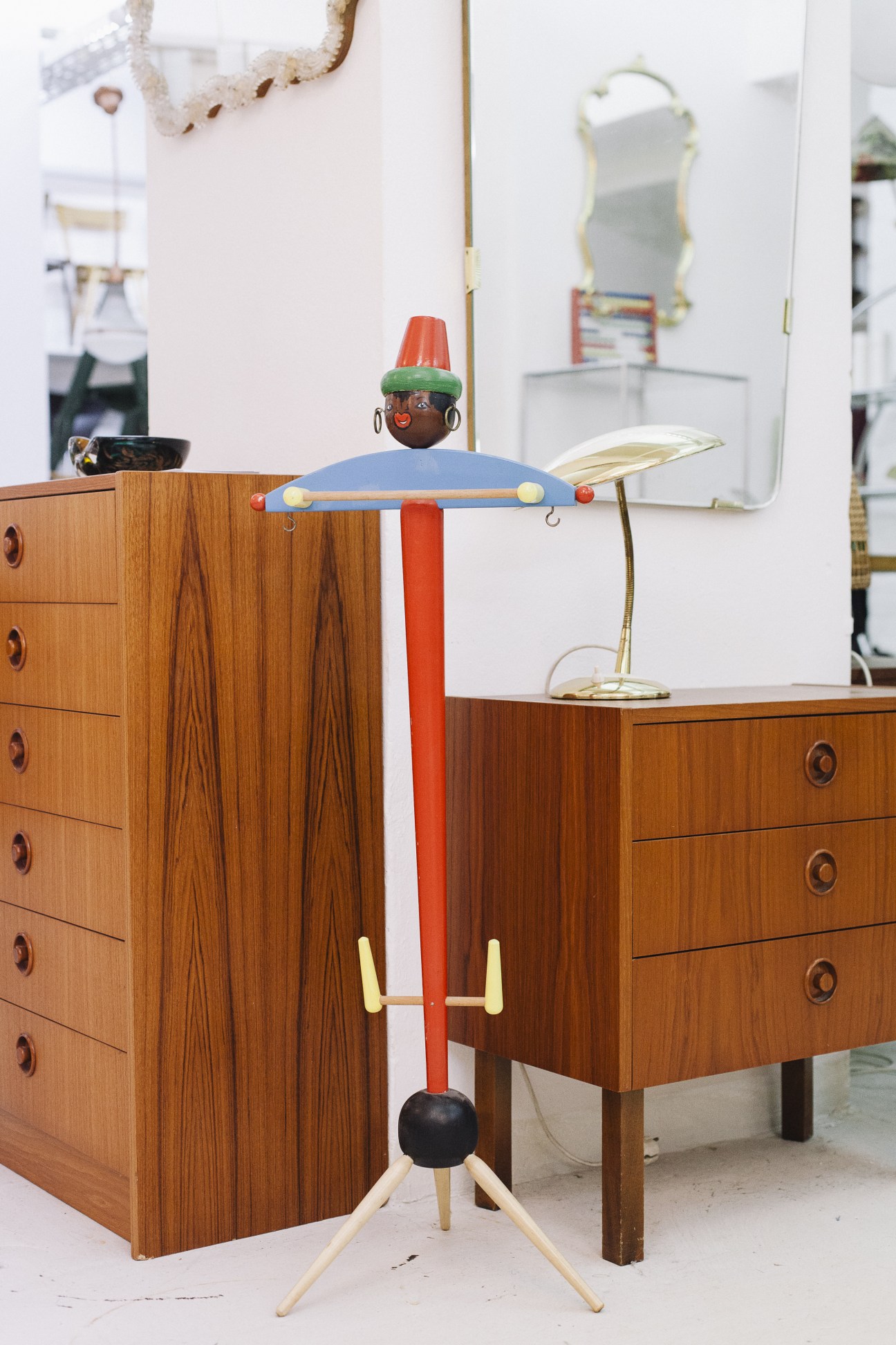 Vintage wooden furniture display with mid-century coat stand featuring colorful character head and articulated arms.
