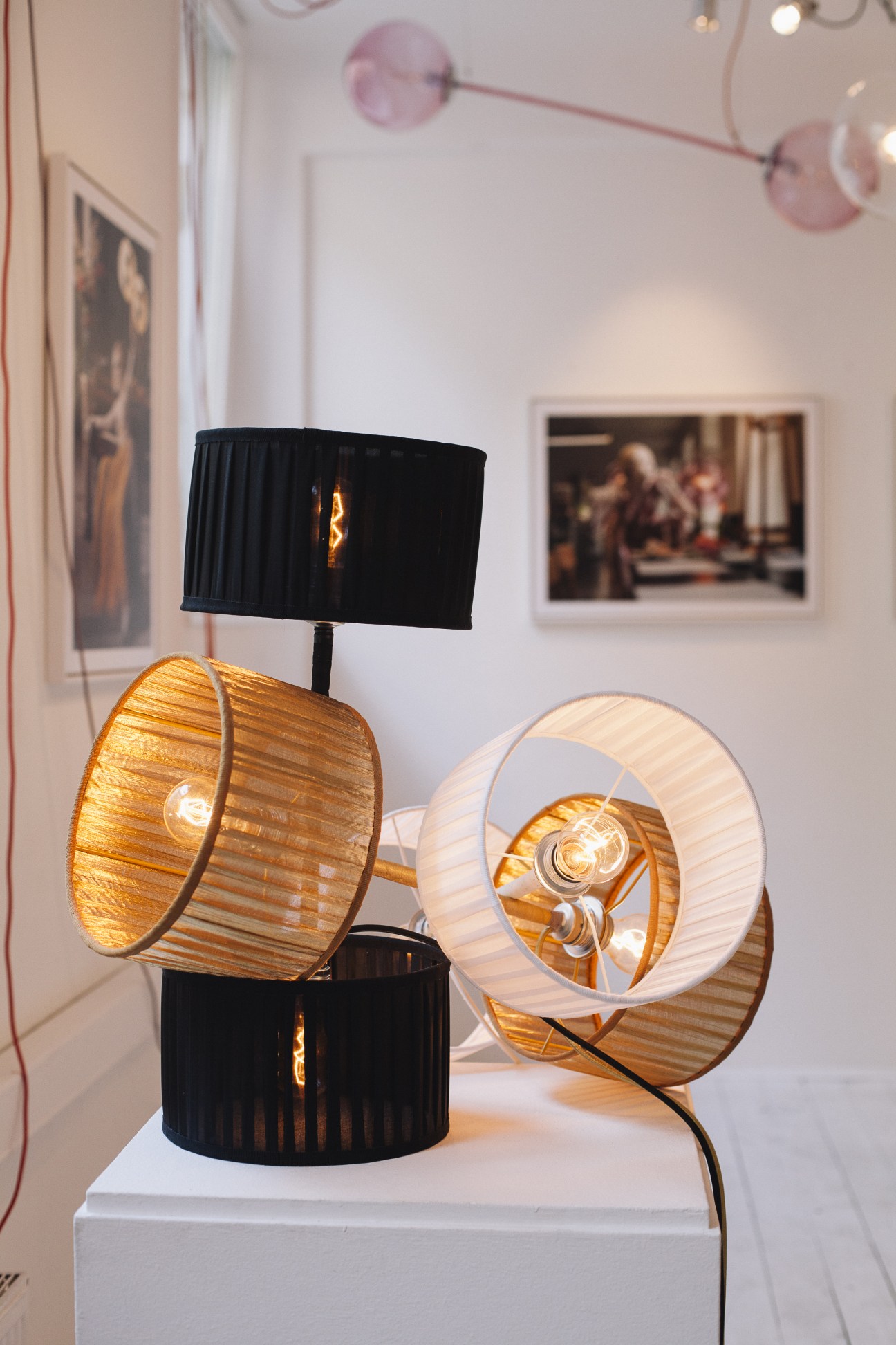 Modern table lamps with pleated fabric shades in black and white displayed in a gallery setting.