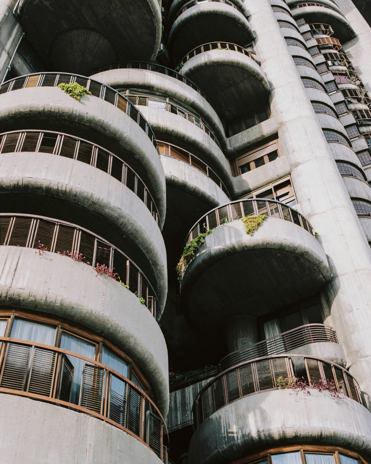Stacked rotating concrete balconies of Torres Blancas with moss-covered curves and vegetation.