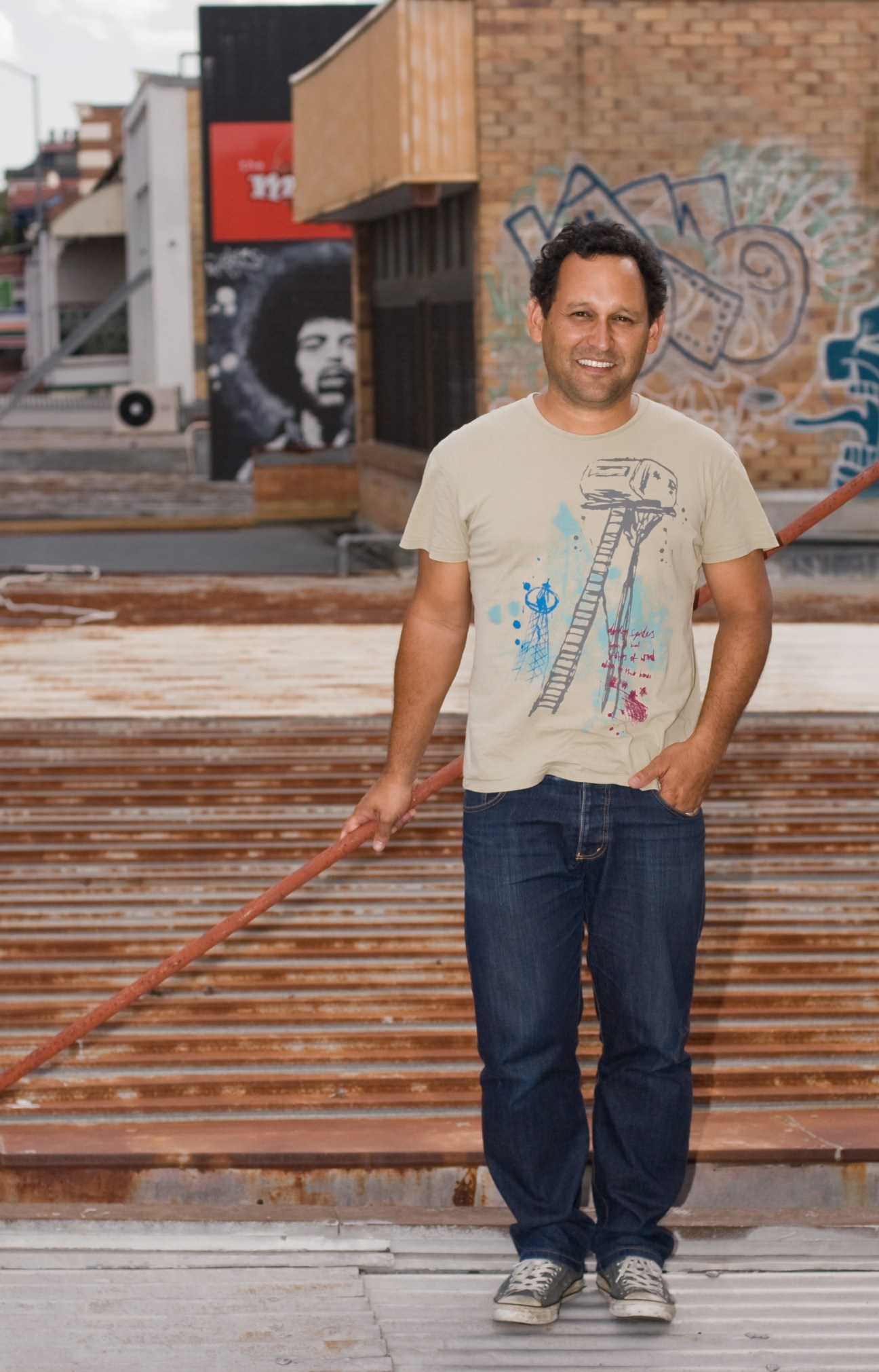 Kevin O'Brien, Queensland's only practising indigenous architect, standing in an urban laneway with street art.
