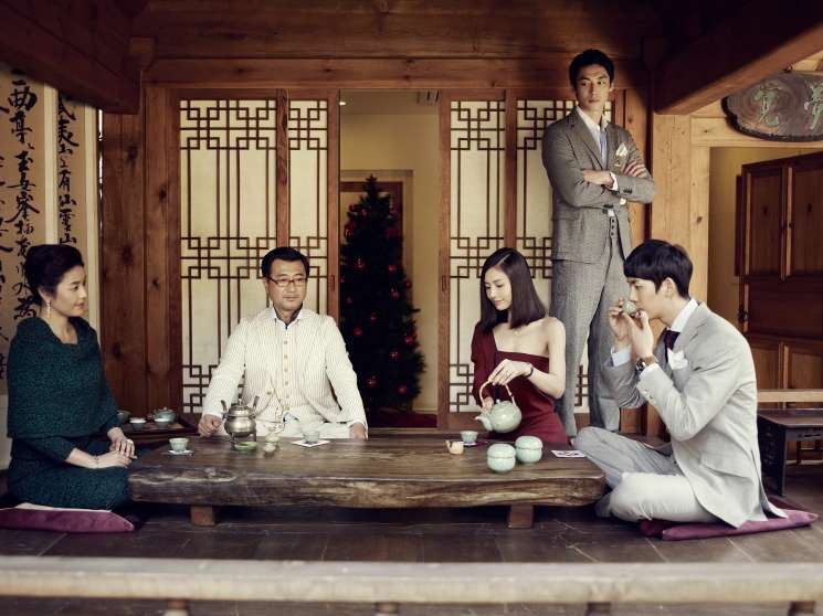 Family gathering around a low wooden table for tea in a traditional Korean room during Christmas.
