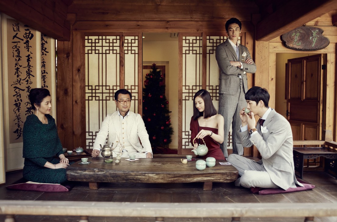Family gathering around a low wooden table for tea in a traditional Korean room during Christmas.