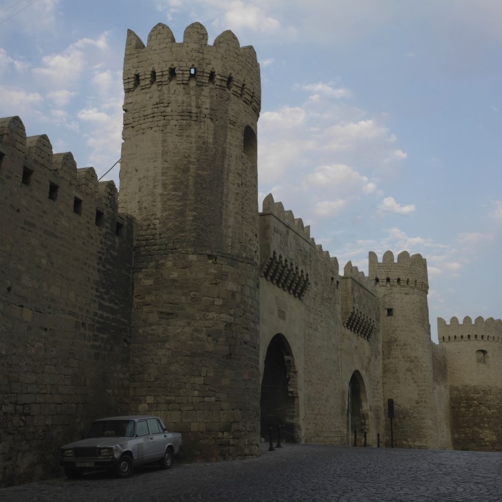 Ancient stone fortification walls and towers of Baku's Old City with arched gateways and crenellations.