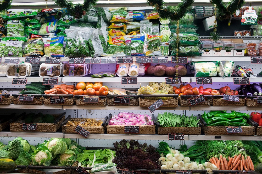 Colorful produce display at a grocery store with fresh vegetables, packaged salads, and price tags.