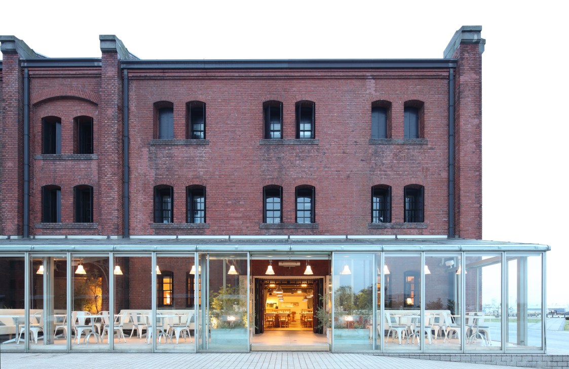 Bills restaurant exterior in a refurbished red brick warehouse with glass storefront and white chairs on a deck.