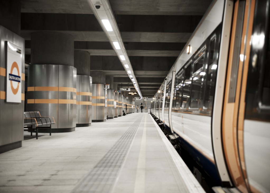 Modern train platform at Dalston overland station with orange and white design accents