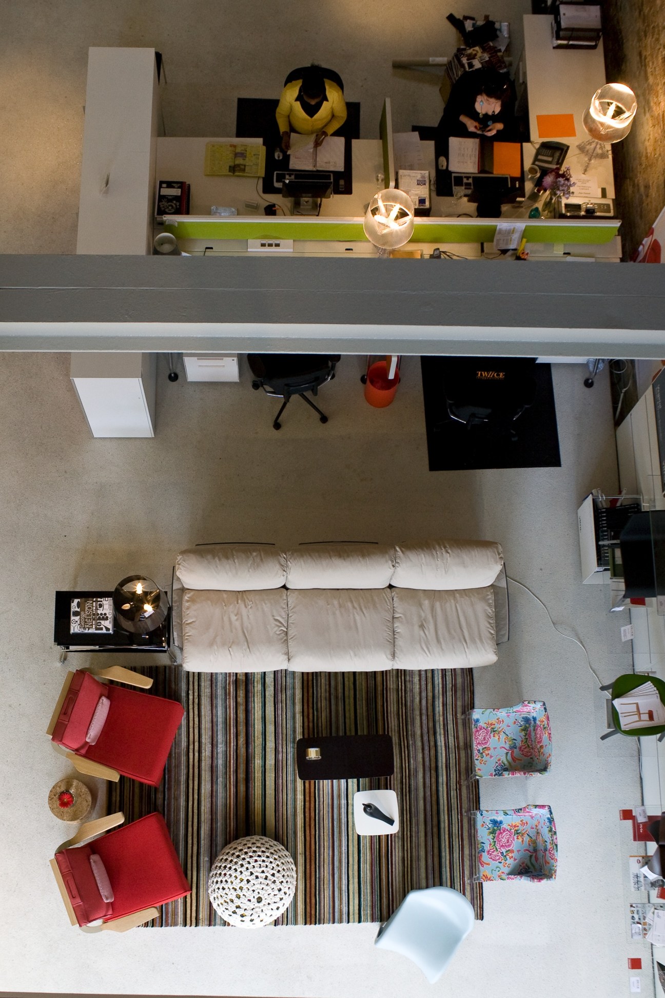 Overhead view of a modern interior design studio workspace with desk, white sofa, and designer furniture at Twiice International.