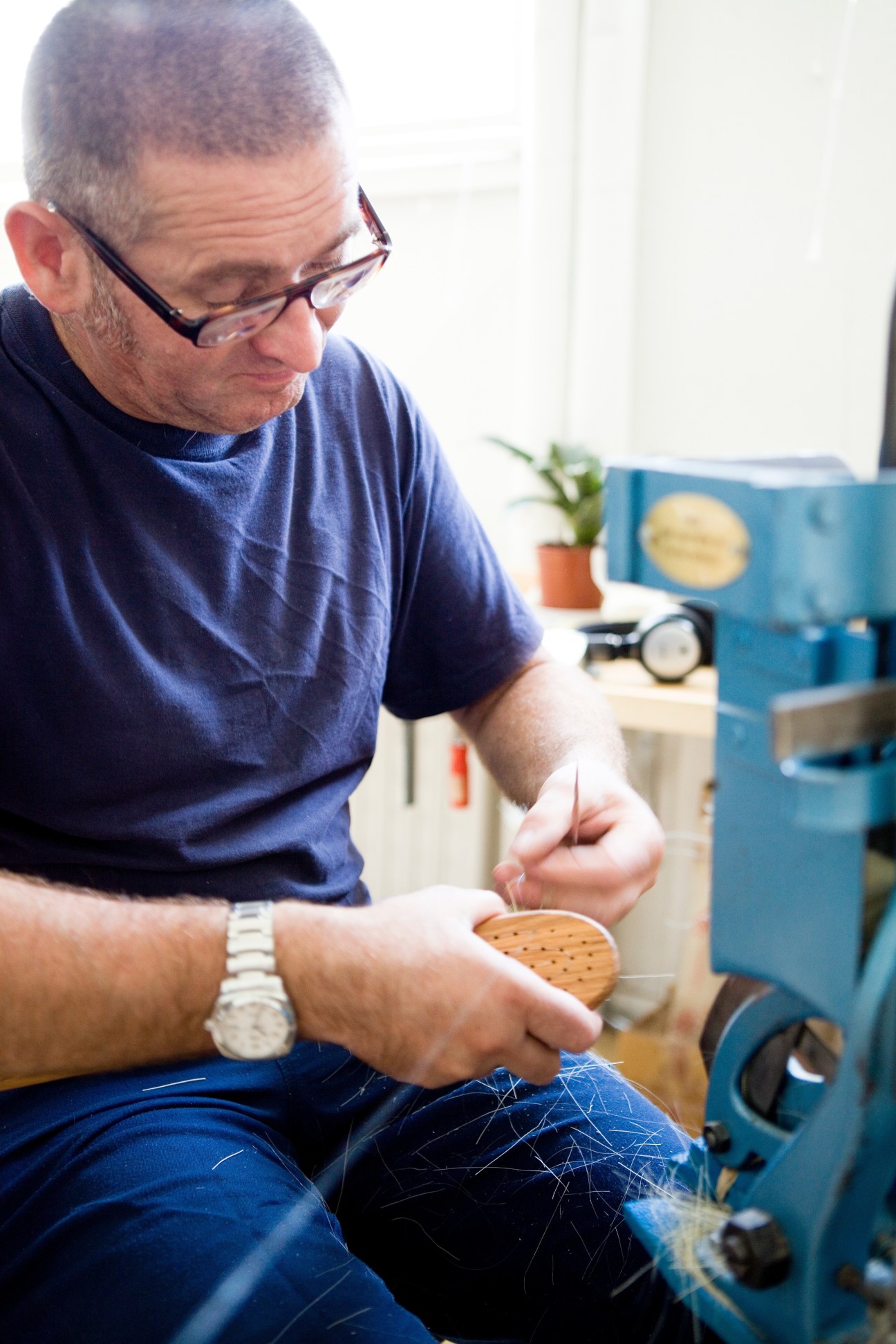Craftsman Dujo Tadic binds bristles to a wooden brush head using stainless steel thread.