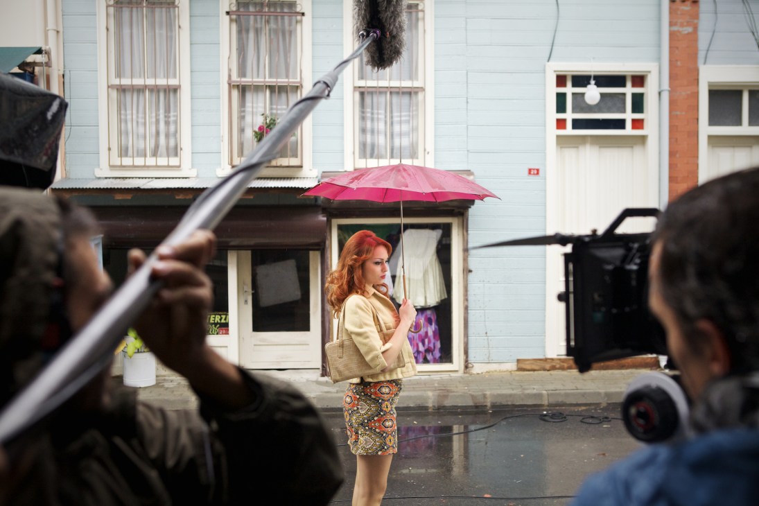 Actress Nilperi Sahinkaya holds a pink umbrella during an on-location film shoot on an Istanbul street.