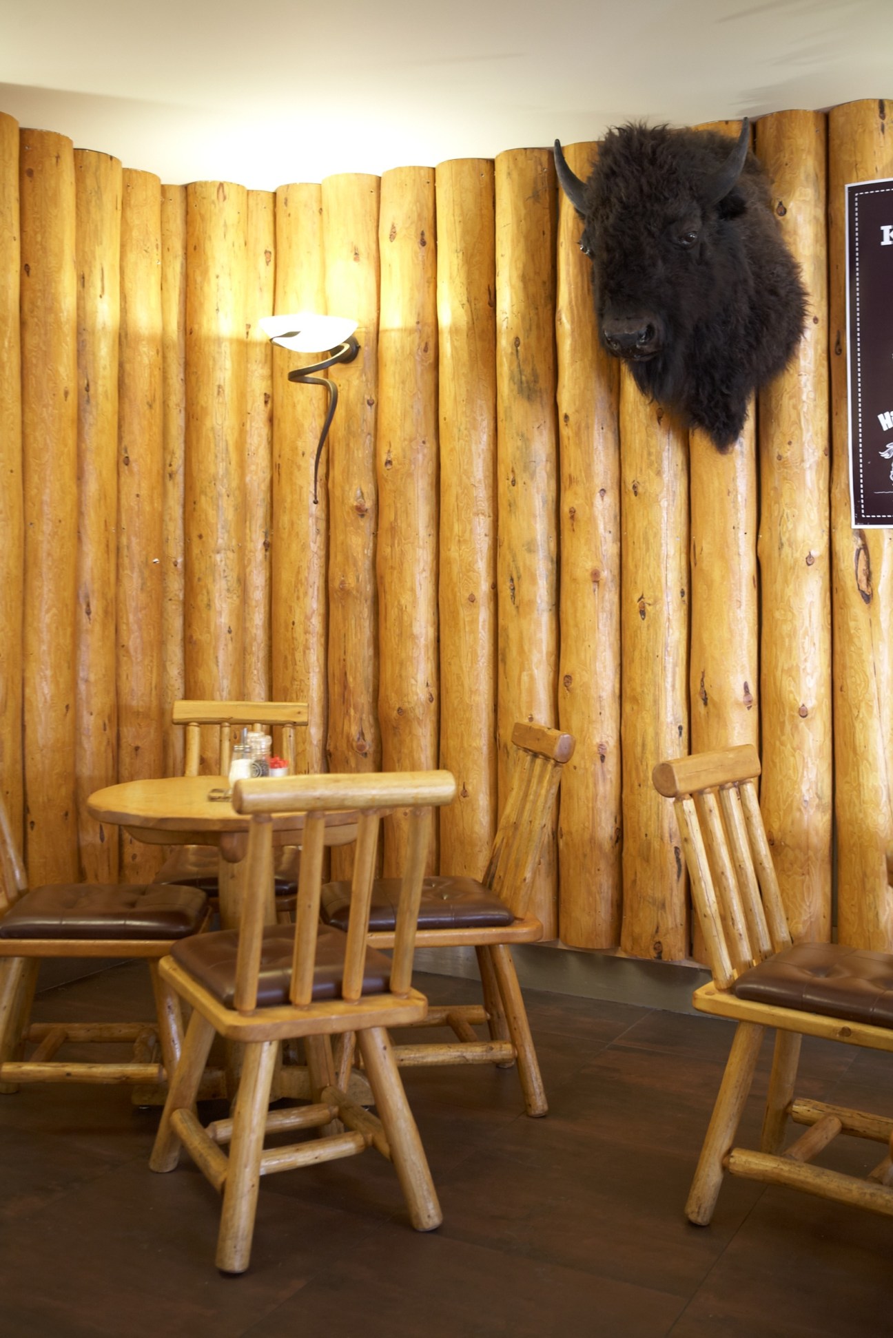 Interior of Kicking Horse café with log cabin-style wooden walls, rustic furniture, and a mounted animal head decoration.