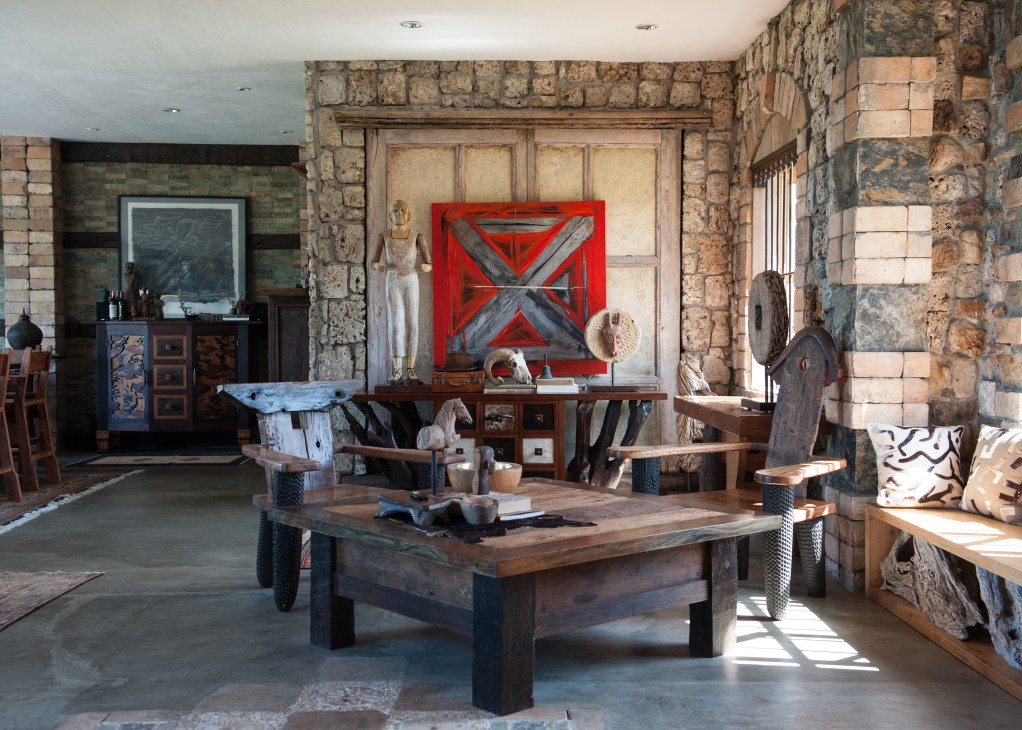 Karl Aguila's home studio with salvaged wood furniture, stone walls, and handmade sculptures.