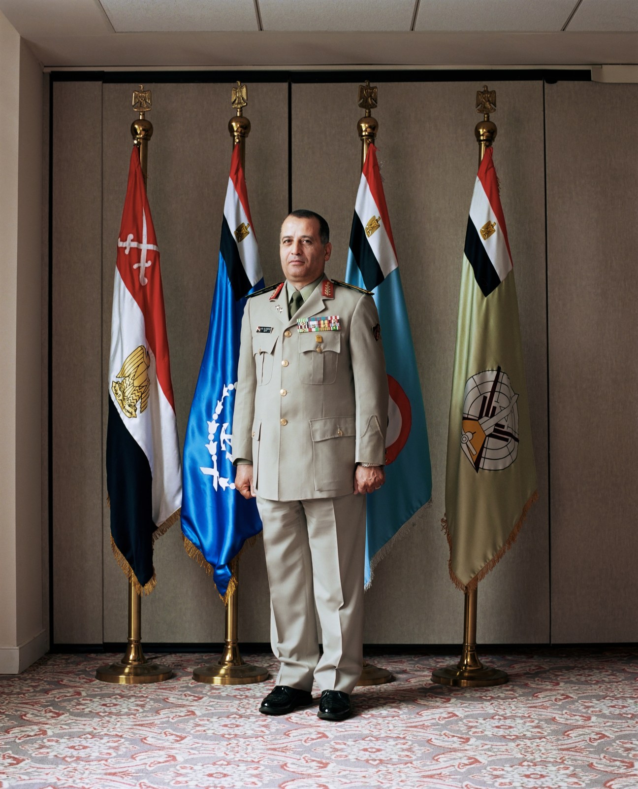 Mohammed Elkeshky, Egyptian defense attaché, in military uniform standing before Egyptian flags.