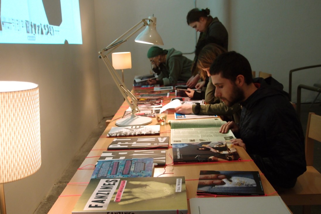 People browsing books and magazines at a long table with desk lamps in the Goethe-Institut Wyoming Building.