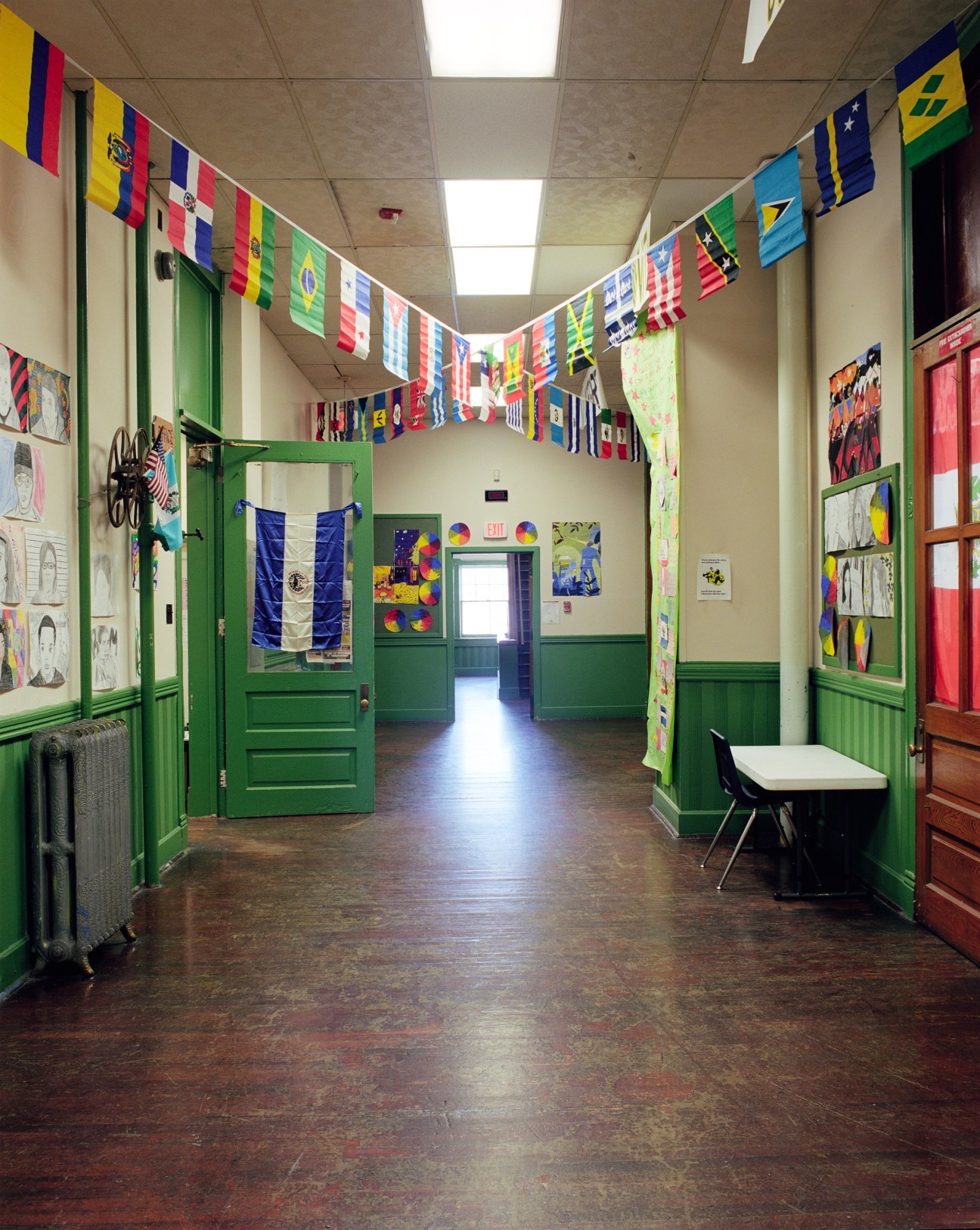 School hallway with green-painted wainscoting decorated with international flags and student artwork.
