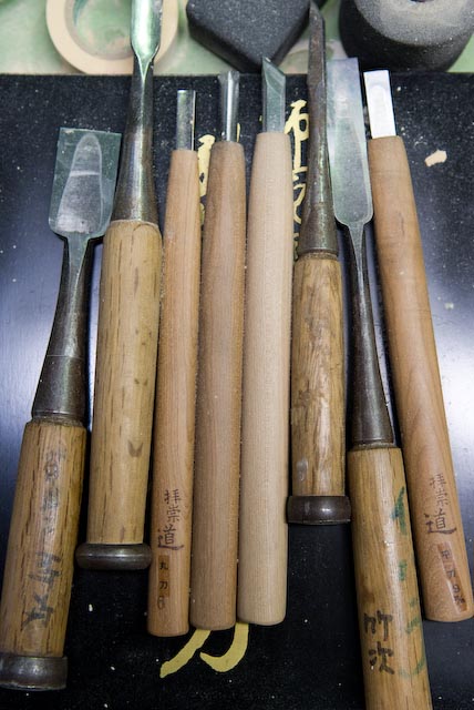 Woodworking tools with wooden handles bearing craftsmen's names engraved in Japanese characters.