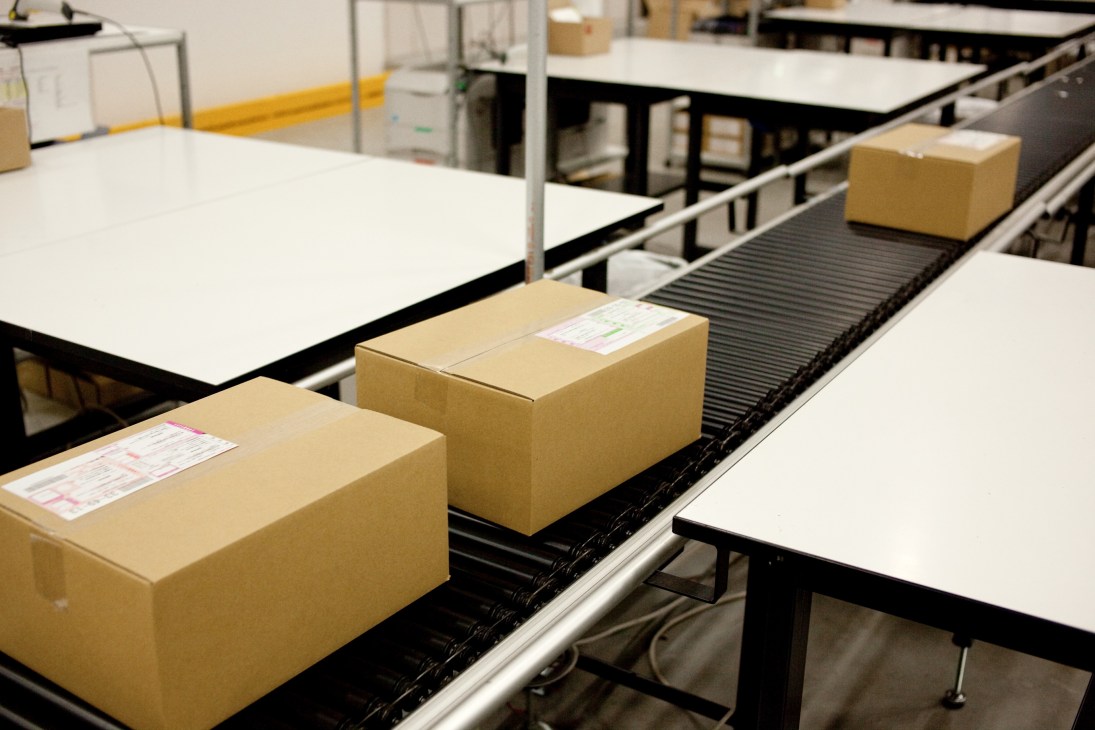 Cardboard boxes on a conveyor belt system in a warehouse shipping facility.