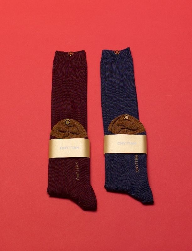 Two pairs of Cnyttan socks in burgundy and navy with brown suede heel details and cream bands.