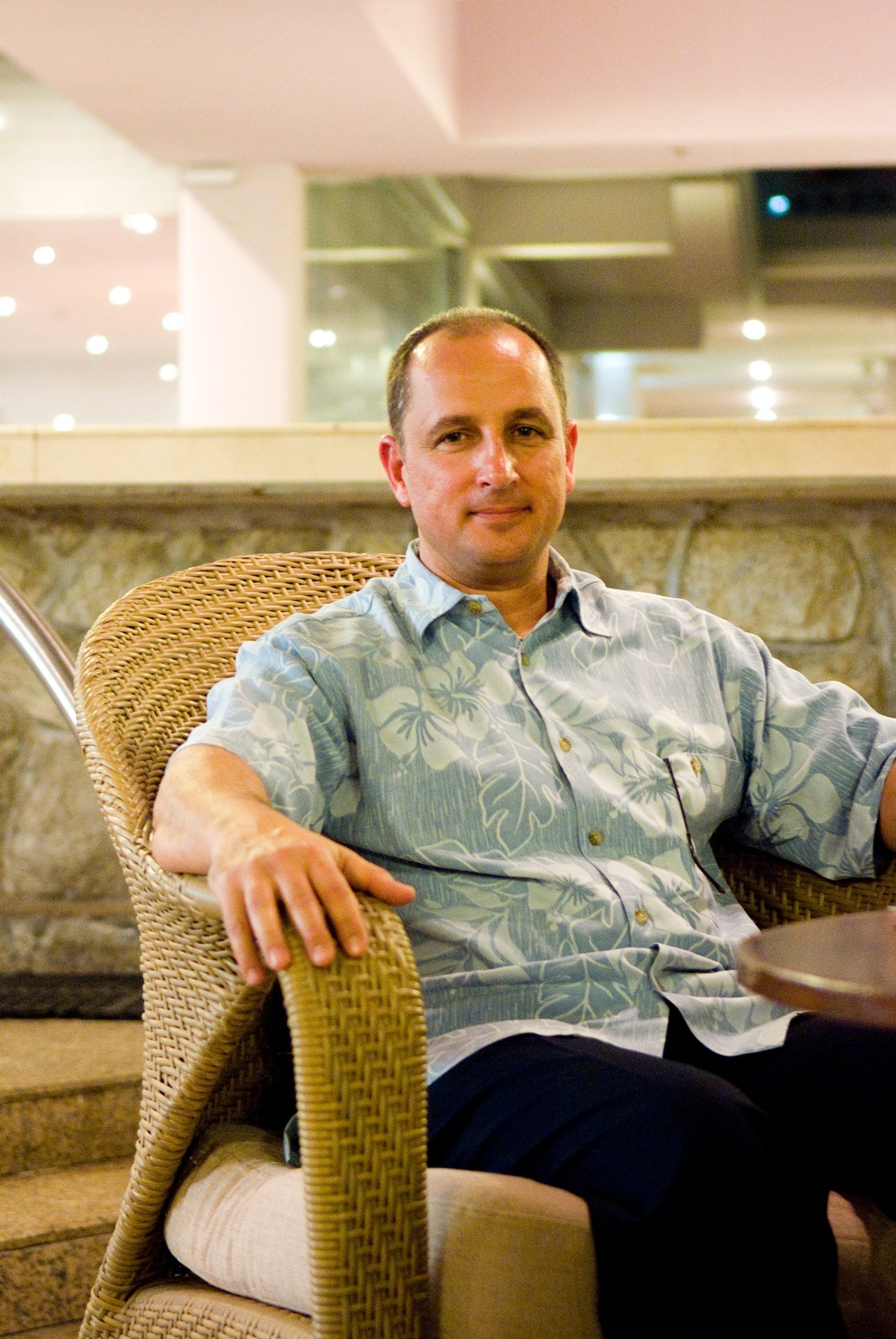 Zig Resiak of RW Armstrong sits in a woven chair wearing a tropical patterned shirt