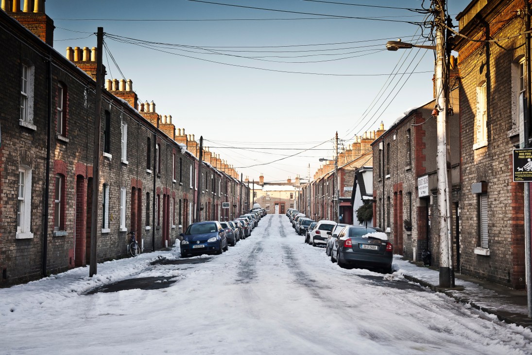Snow-covered street lined with brick terraced houses in Dublin's Stoneybatter neighborhood.