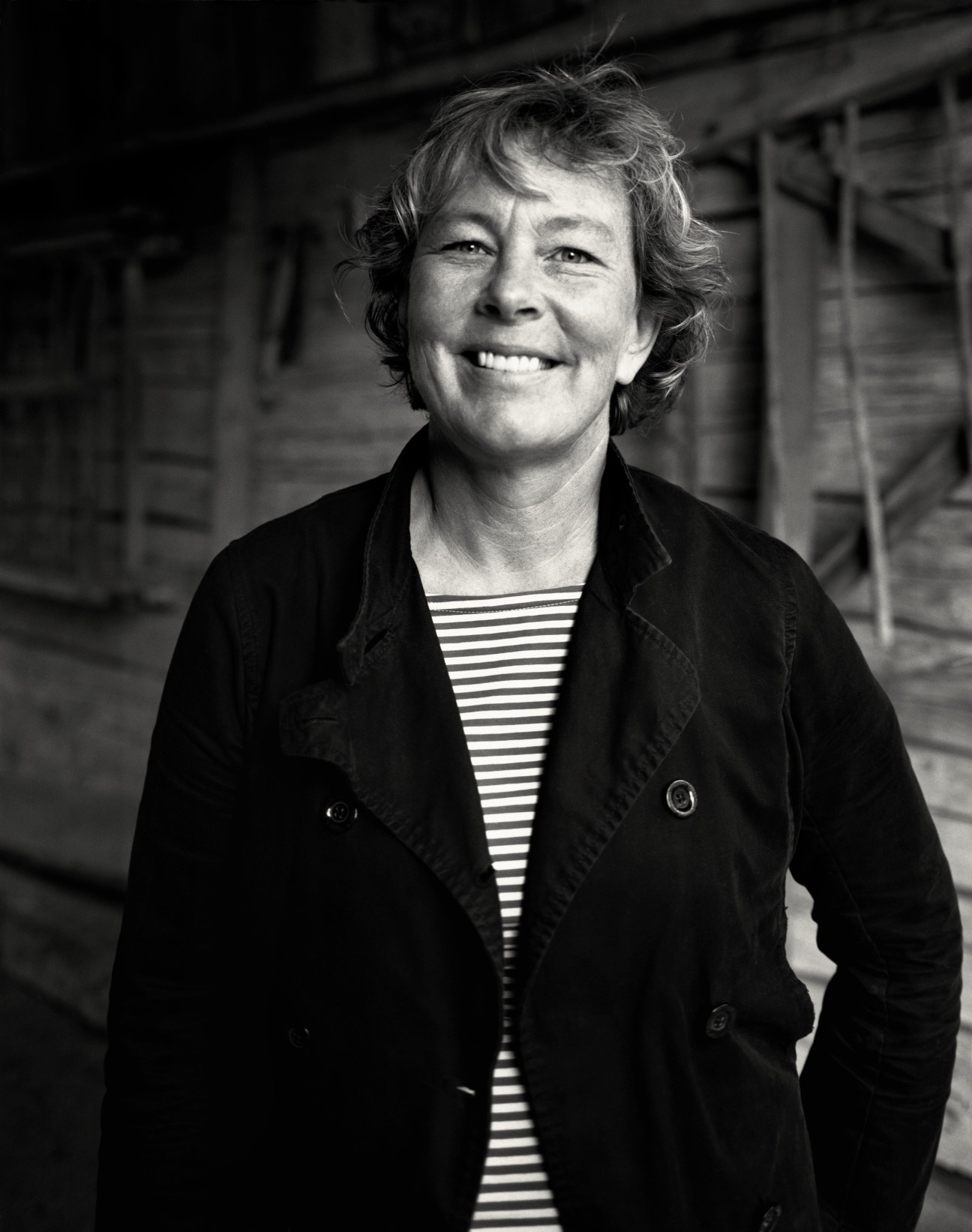Black and white portrait of Stina Lindholm, industrial designer, smiling at the camera wearing a striped shirt and dark blazer.