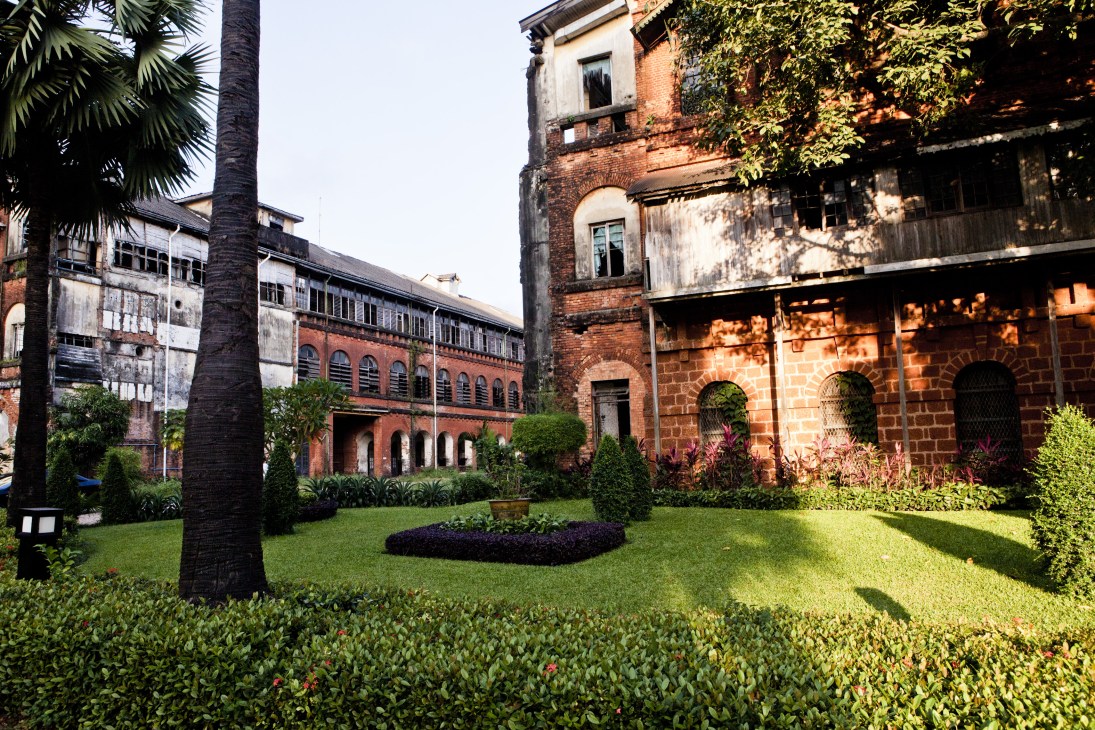 Former railway headquarters courtyard in Rangoon with red brick colonial architecture and manicured gardens.